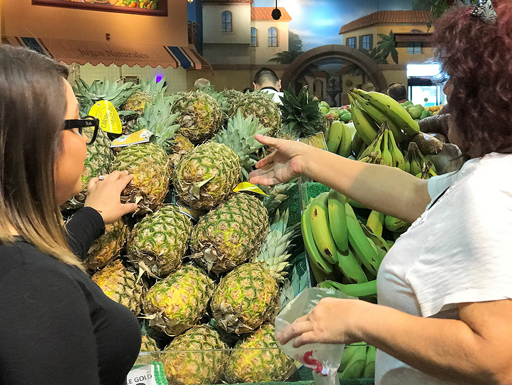 Woman helping another choose fruits